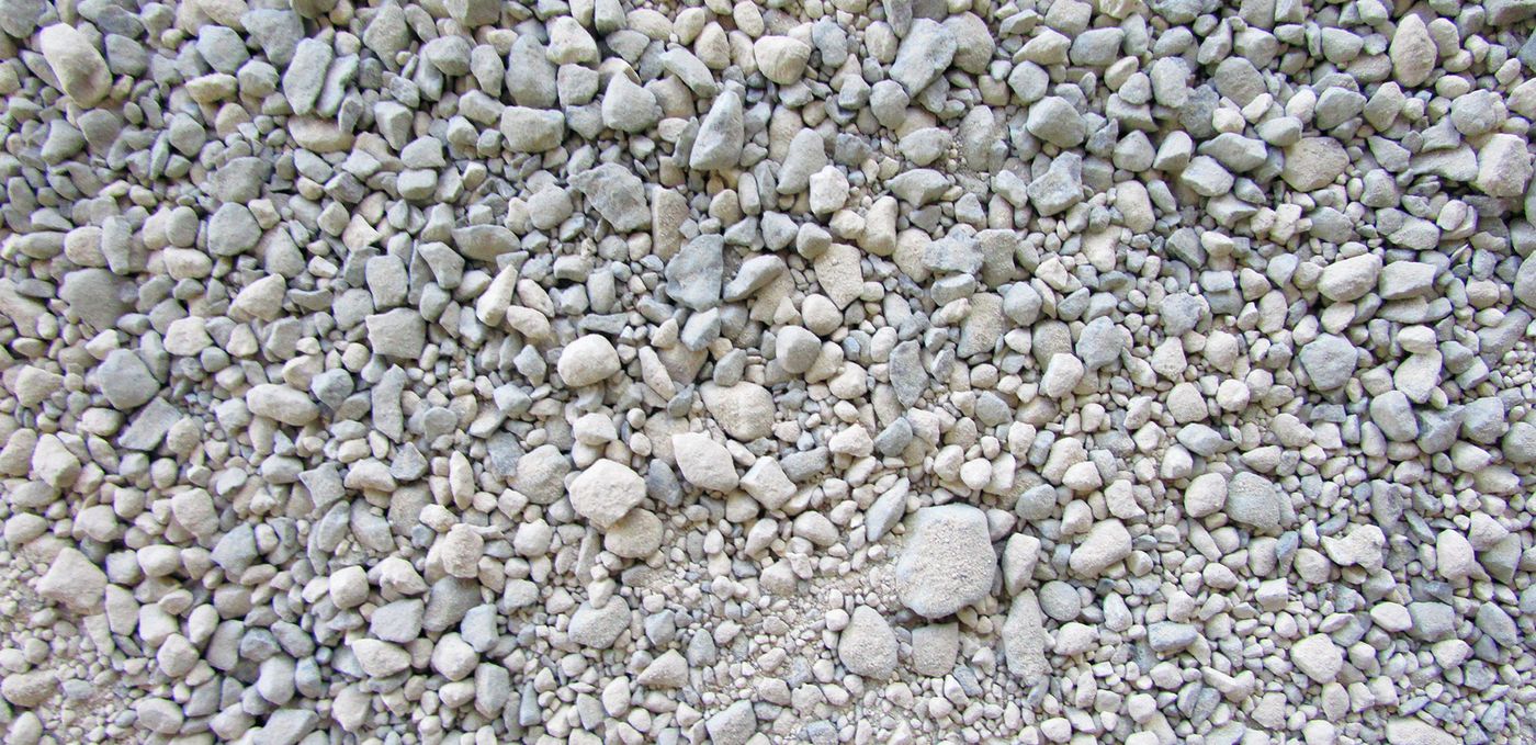 Photo: light grey stone grit with uniform particle size, containing larger grains, spread flat