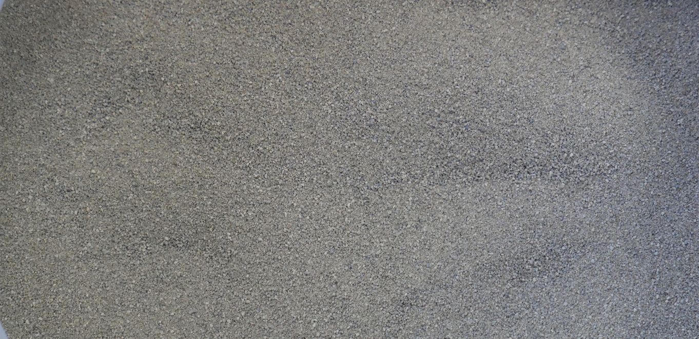 Image : poudre de roche finement granulée, gris moyen et étalée sur une surface plane