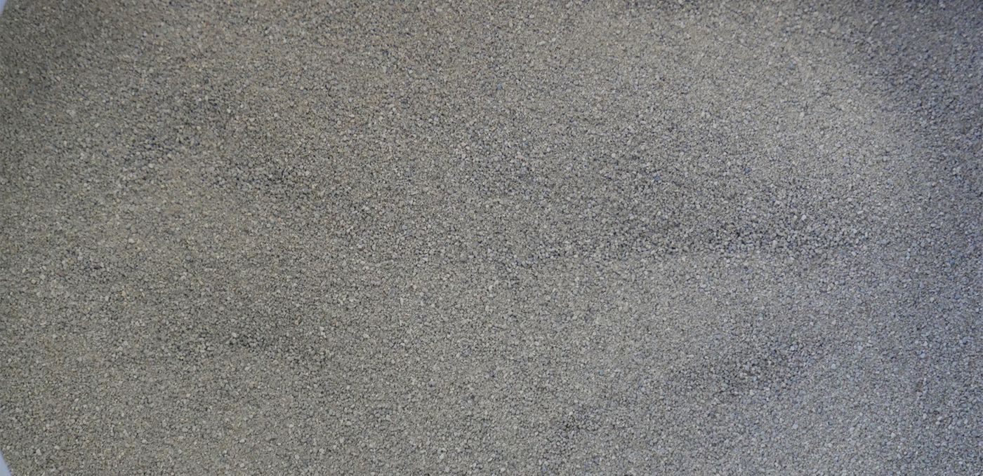 Image : poudre de roche finement granulée, gris moyen et étalée sur une surface plane